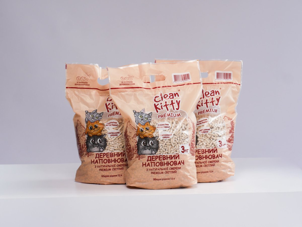Tre sacchi Clean Kitty PREMIUM da 3 kg di lettiera naturale di abete bianco su una superficie bianca